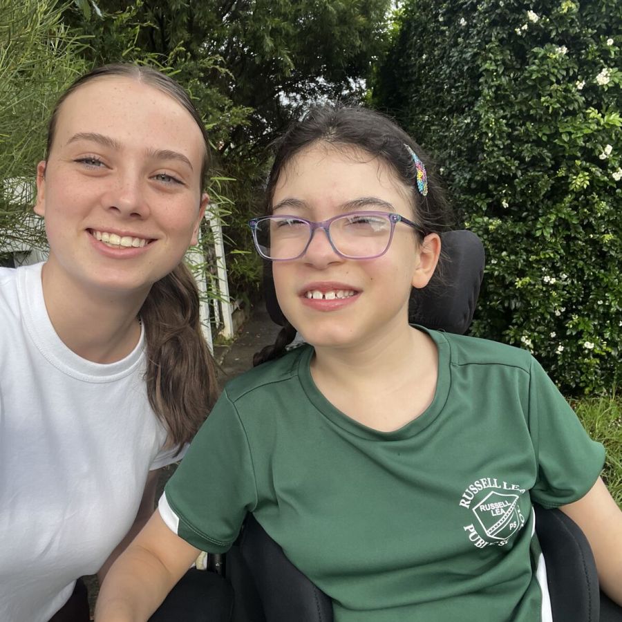 Participant and support worker smiling together outdoors