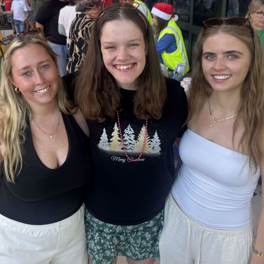 Three people smiling together at a community event
